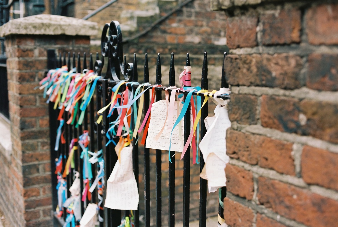 Memorial ribbons tied to the iron gate of Crossbones Garden.