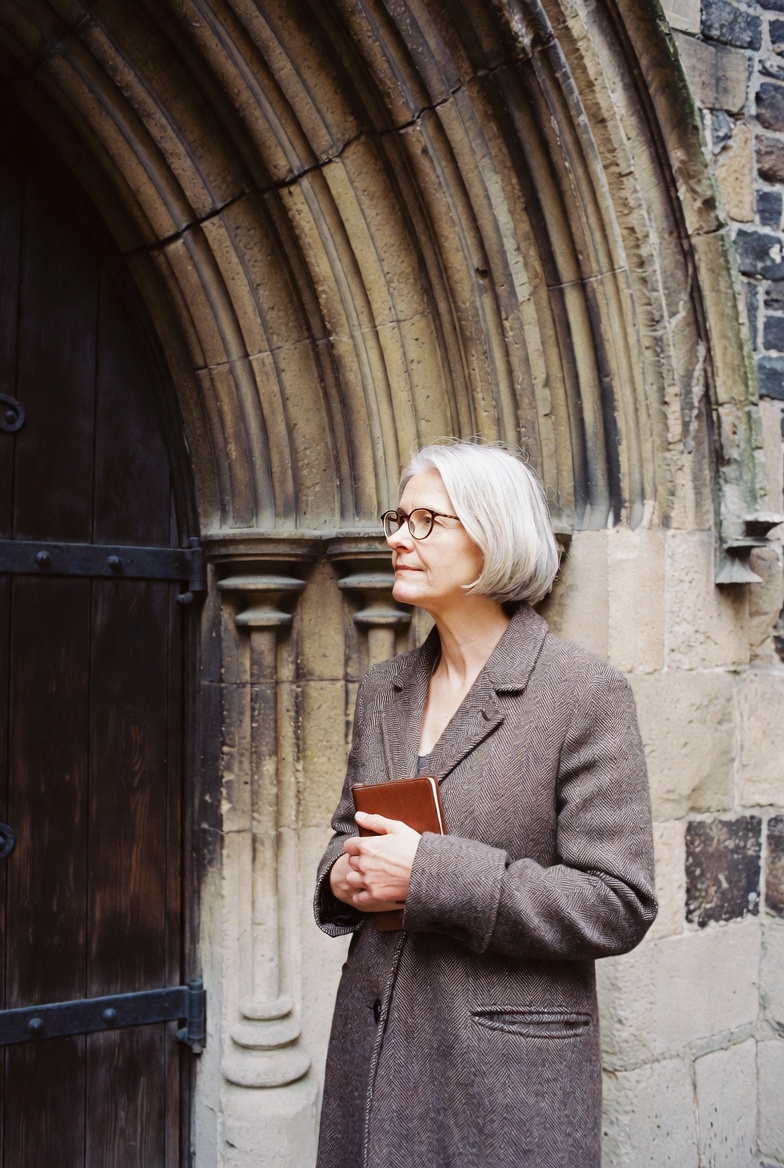 Margaret Trelawney photographed beside the carved south door of an English Gothic church.
